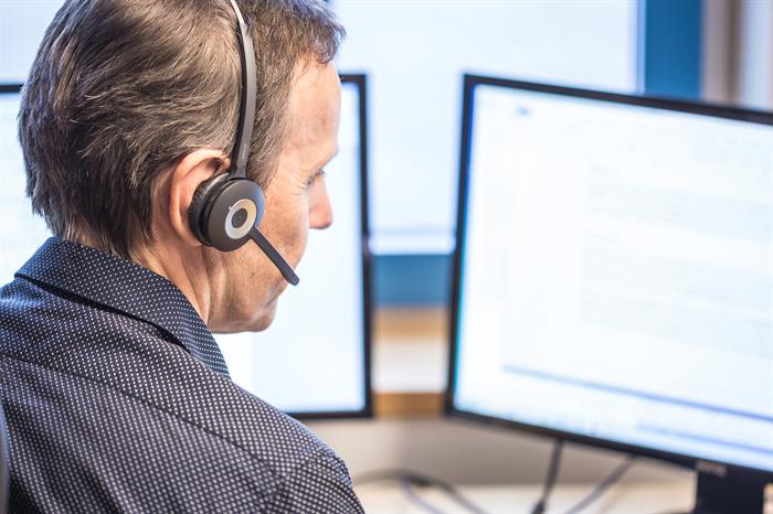Mann med headset foran en datamaskin
